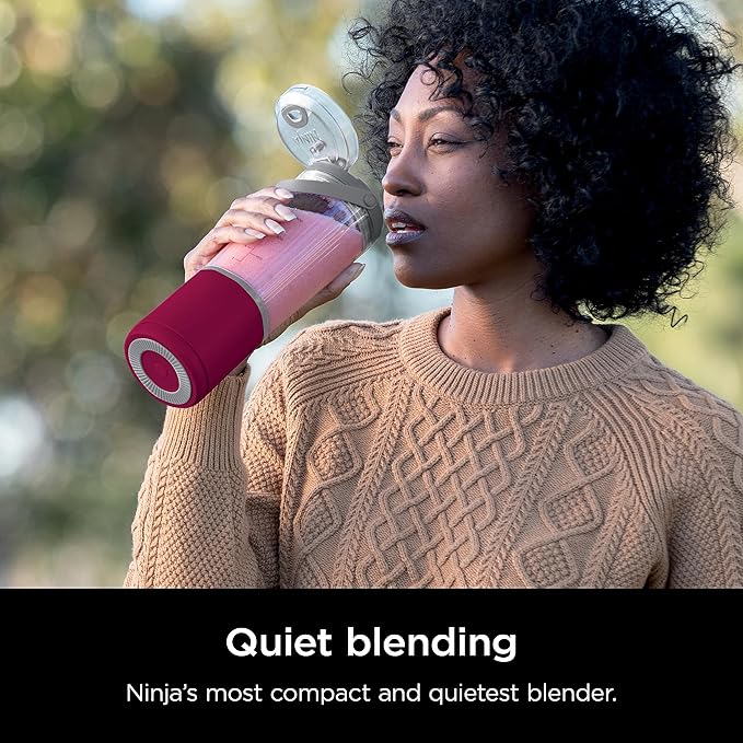 Portable smoothie blender with magenta body being sipped from outdoors