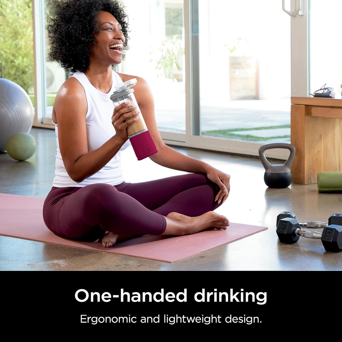 Portable smoothie blender with magenta body and clear jar while drinking