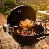Rotisserie chicken on black grill with rotisserie rod and spit forks