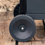 BBQ grill caster wheel with metal axle, close-up on dark rubber tire